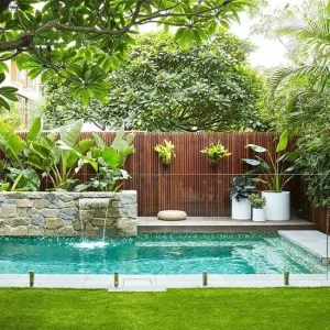 A green garden area with a pool and glass panes.
