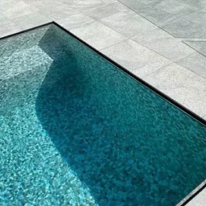 Silver poolside pavers around a swimming pool.